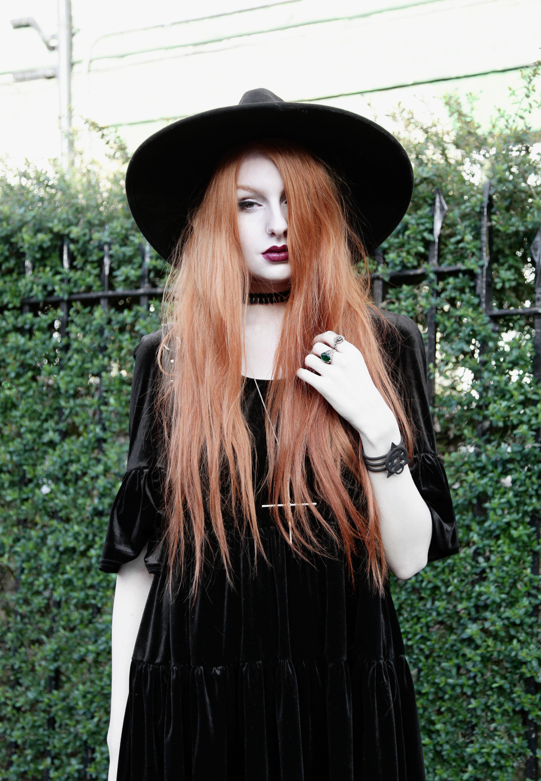 Olivia Emily wears Asos Reclaimed Vintage tiered black velvet dress, Killstar Witch Brim hat, and Kiki Minchin Classic Cross silver necklace