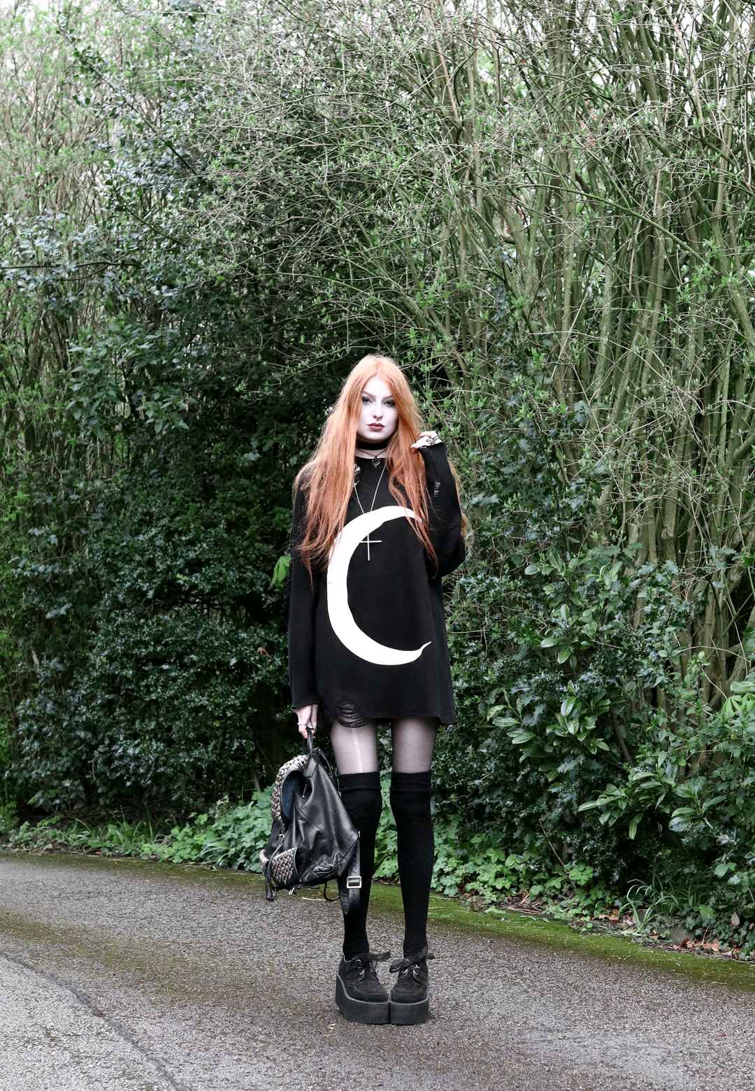 Olivia Emily wears Killstar Luna moon print knit oversized jumper, Asos thigh high socks, Underground triple sole creepers, and Rebecca Minkoff backpack