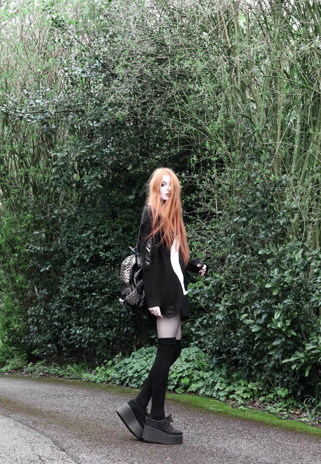 Olivia Emily wears Killstar Luna moon print knit oversized jumper, Asos thigh high socks, Underground triple sole creepers, and Rebecca Minkoff backpack