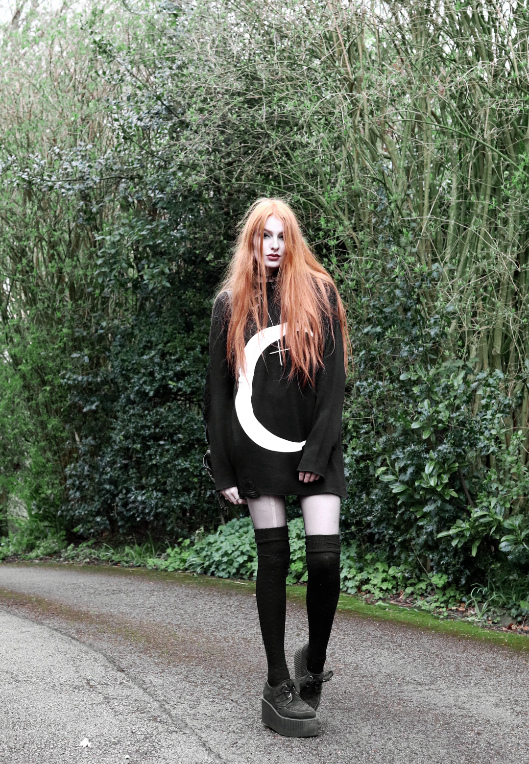 Olivia Emily wears Killstar Luna moon print knit oversized jumper, Asos thigh high socks, Underground triple sole creepers, and Rebecca Minkoff backpack