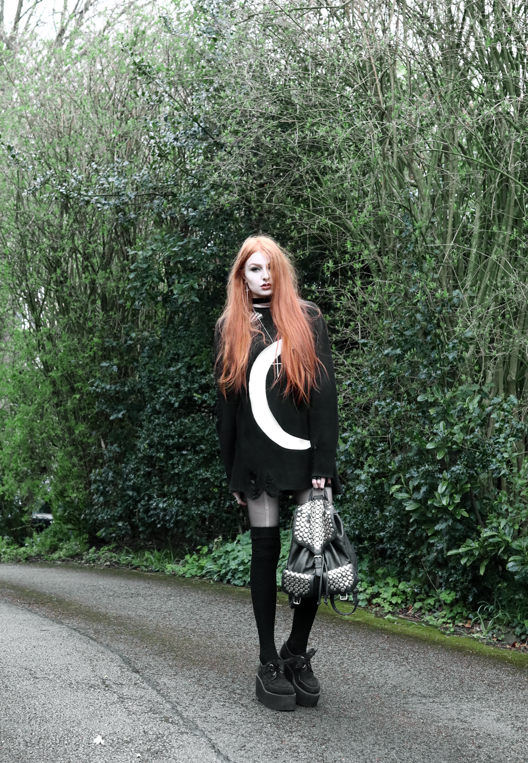 Olivia Emily wears Killstar Luna moon print knit oversized jumper, Asos thigh high socks, Underground triple sole creepers, and Rebecca Minkoff backpack