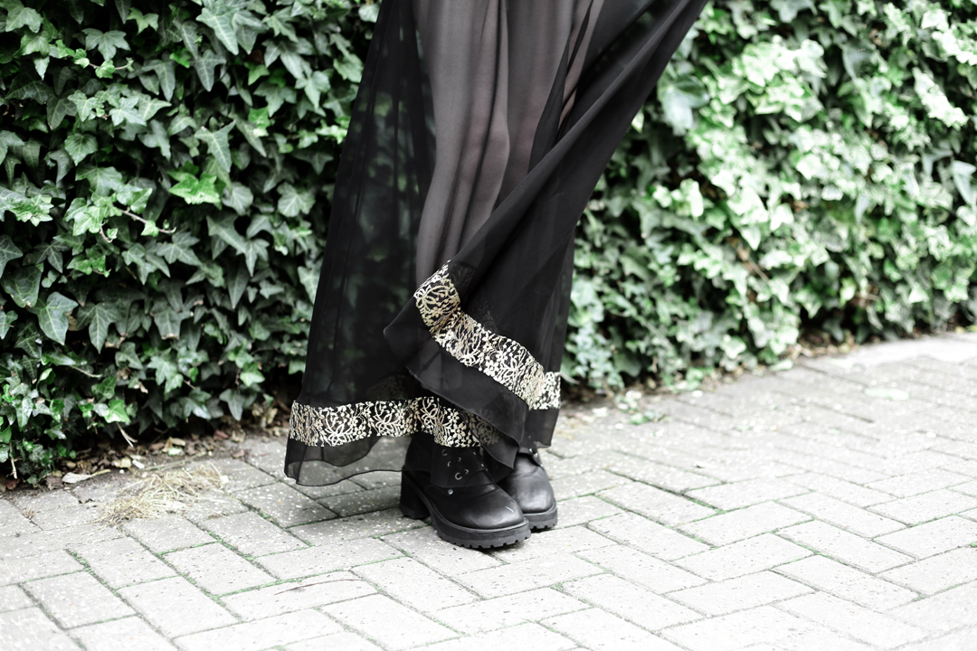 Olivia Emily wears Dark Thorn Chastity sheer maxi skirt with gold lace insert, and Unif Dedi boots