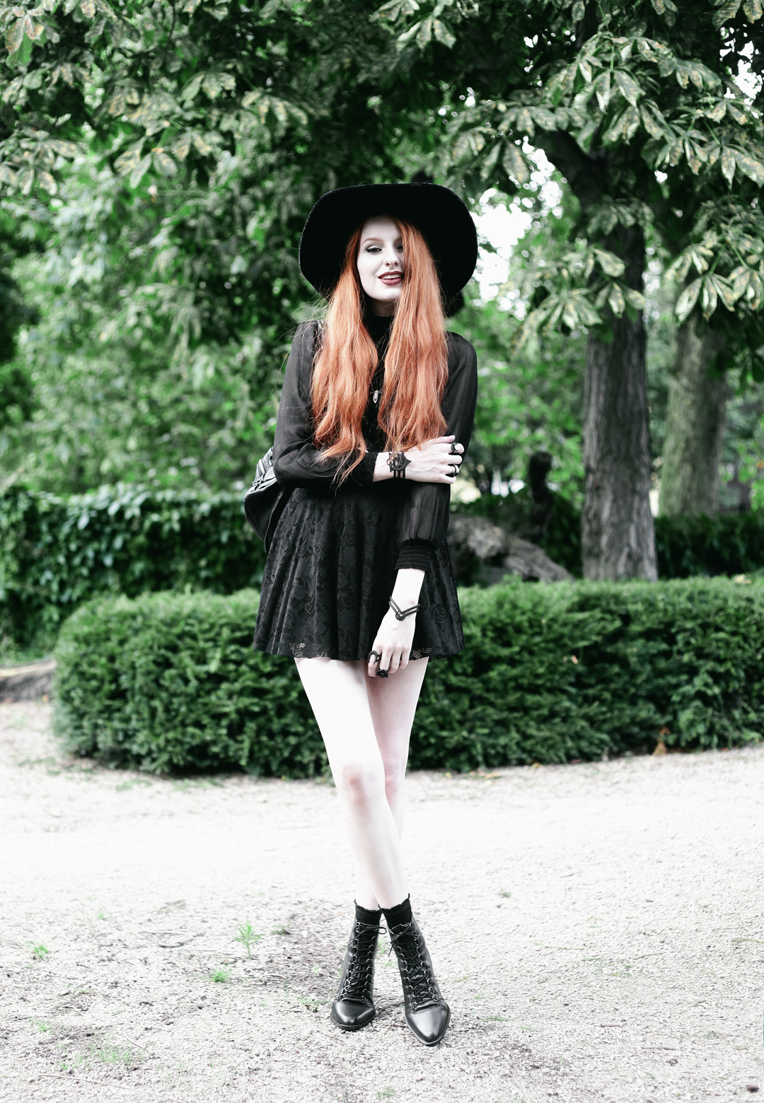 Olivia Emily wears Asos Sheer Shirt, Black Milk Black Lace Skater Dress, Killstar Velvet Witch Brim Hat, Zana Bayne Cincher Waist Belt, and Asos Ariana Lace Up Boots