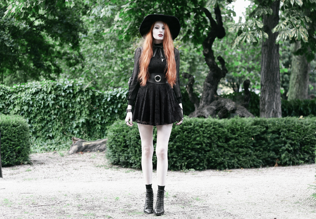 Olivia Emily wears Asos Sheer Shirt, Black Milk Black Lace Skater Dress, Killstar Velvet Witch Brim Hat, Valfre Bowie Choker, Zana Bayne Cincher Waist Belt, and Asos Ariana Lace Up Boots