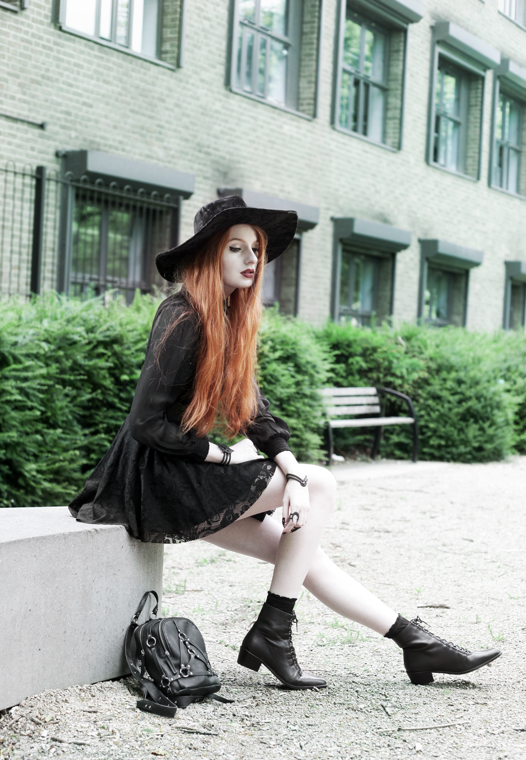 Olivia Emily wears Asos Sheer Shirt, Black Milk Black Lace Skater Dress, Killstar Velvet Witch Brim Hat, Zana Bayne Cincher Waist Belt, Unif Bound Mini Backpack and Asos Ariana Lace Up Boots