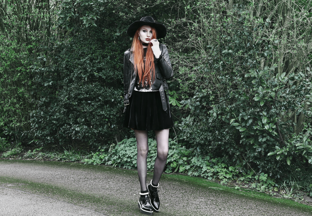 Olivia Emily wears Killstar Lestat shredded knit crop sweater, Killstar Velvet Witch Brim Hat, Unif Biker Jacket, Black Velvet Skirt