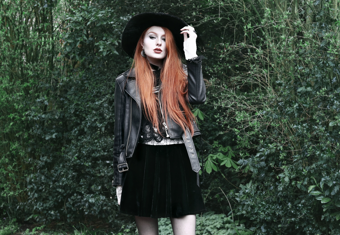 Olivia Emily wears Killstar Lestat shredded knit crop sweater, Killstar Velvet Witch Brim Hat, Unif Biker Jacket, Black Velvet Skirt