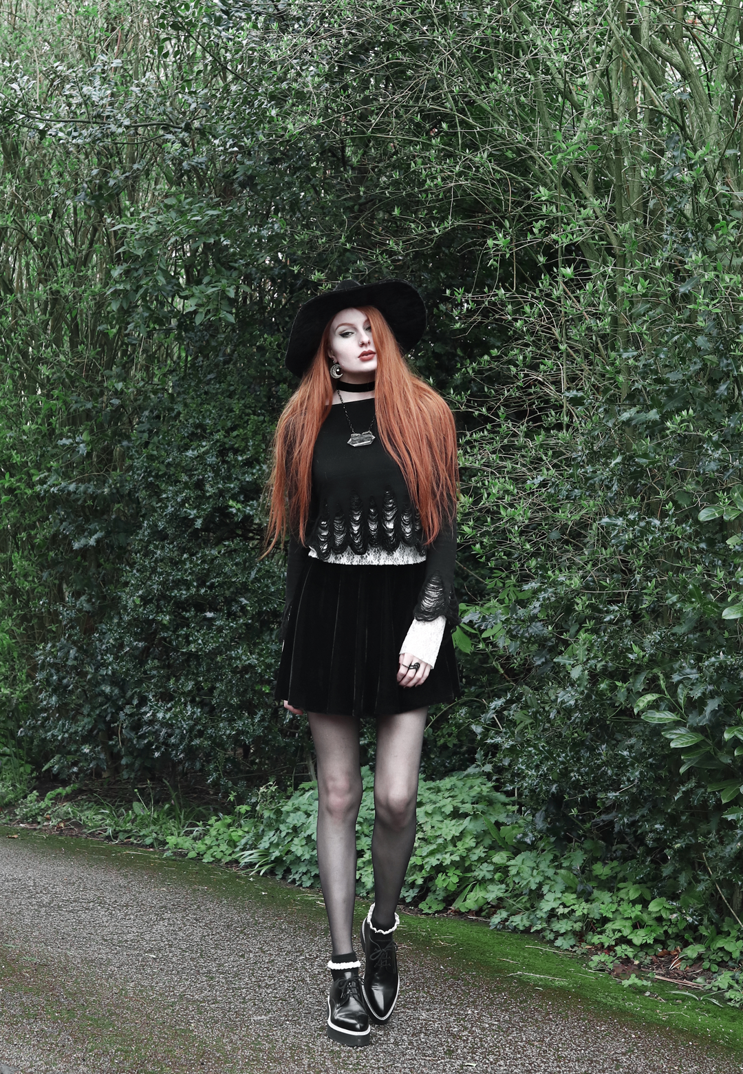 Olivia Emily wears Killstar Lestat shredded knit crop sweater, Killstar Velvet Witch Brim Hat, Black Velvet Skirt, Alexander McQueen platform shoes