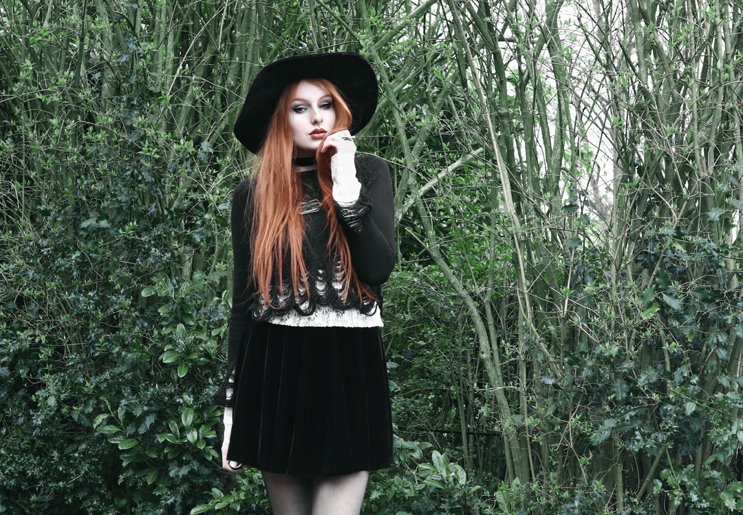 Olivia Emily wears Killstar Lestat shredded knit crop sweater, Killstar Velvet Witch Brim Hat, Black Velvet Skirt