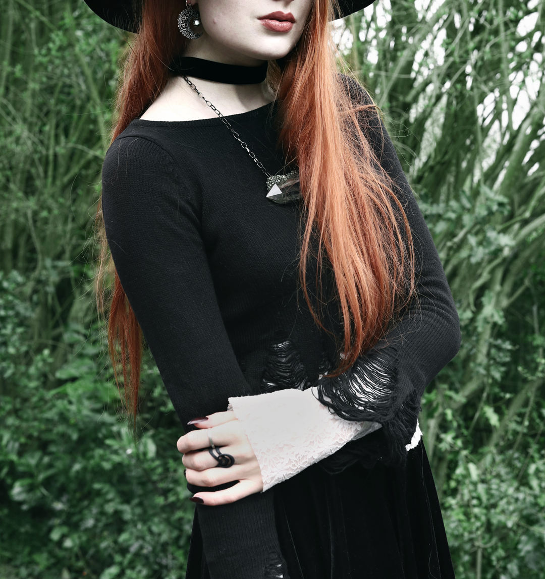 Olivia Emily wears Killstar Lestat shredded knit crop sweater, Regalrose Velvet Choker, Serpents Club Quartz necklace, Nyxturna Spike Ring, Rogue And Wolf matte black ring