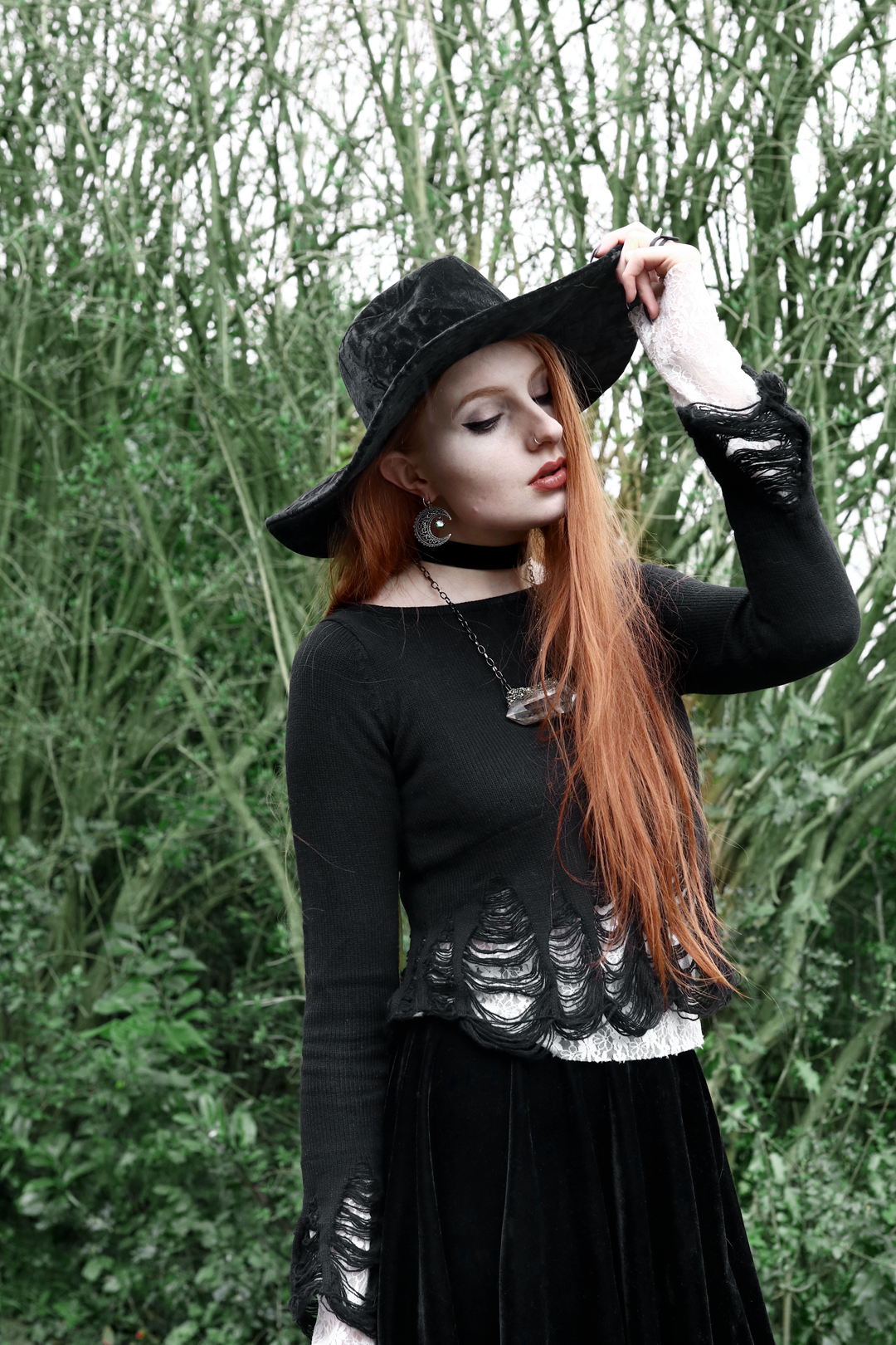 Olivia Emily wears Killstar Lestat shredded knit crop sweater, Killstar Velvet Witch Brim hat, Regalrose Velvet Choker, Serpents Club Quartz necklace, Nyxturna Spike Ring, Rogue And Wolf matte black ring