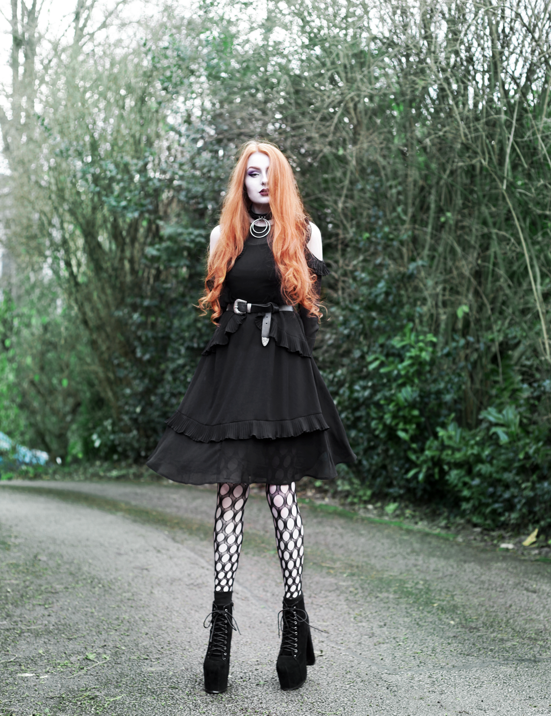 Olivia Emily wears Asos black ruffle midi dress, Killstar Dita Slave collar choker, Asos western belt, Asos pothole tights, and faux suede platform heels boots