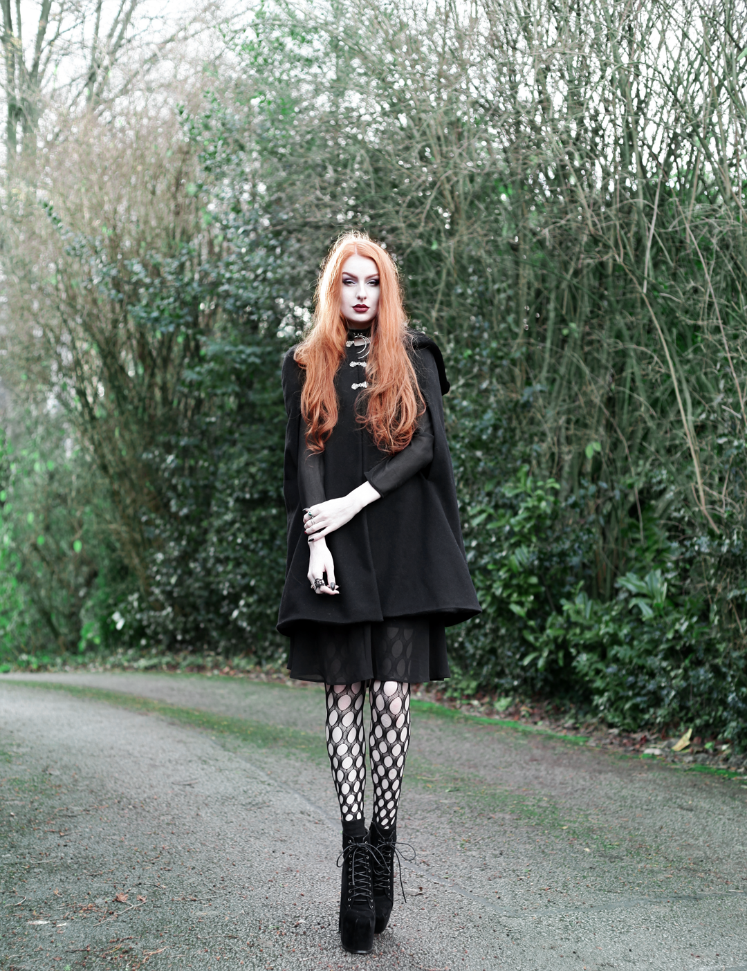 Olivia Emily wears Dark Thorn Clothing Myrtle Cape, Asos black ruffle midi dress, Killstar Dita Slave collar choker, Asos western belt, Asos pothole tights, faux suede platform heels boots