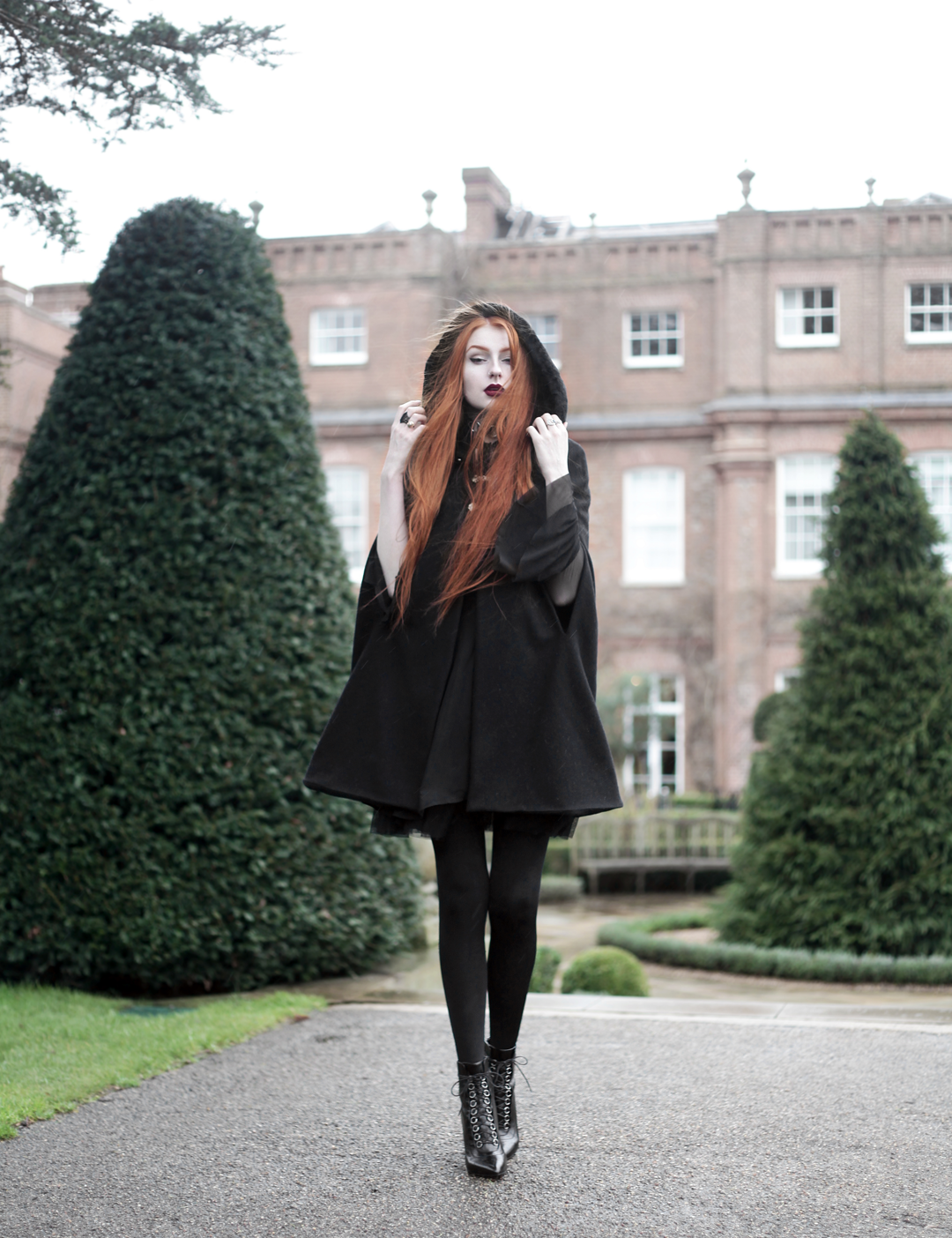 Olivia Emily wears Dark Thorn Clothing Cape, Killstar Nu Decay Dress, and Saint Laurent Fetish Ankle Boots