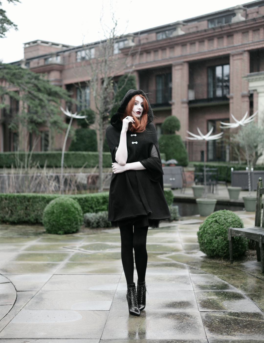 Olivia Emily wears Dark Thorn Clothing Cape, Killstar Nu Decay Dress, and Saint Laurent Fetish Ankle Boots