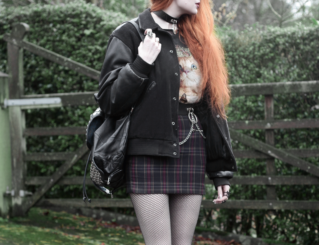 Olivia Emily wears Vintage Cat Tee, fishnet long sleeve top, Mary Wyatt Belt, Plaid Skirt, and Rebecca Minkoff Backpack