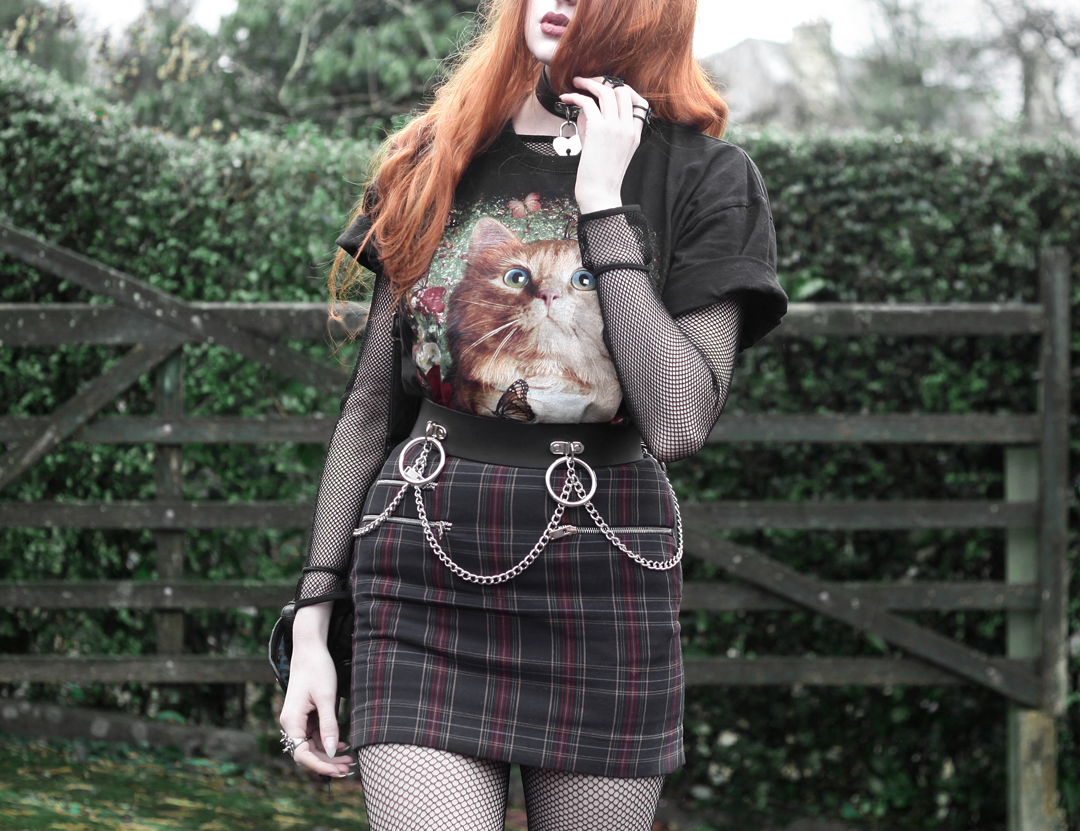 Olivia Emily wears Vintage Cat Tee, fishnet long sleeve top, Mary Wyatt Belt, Plaid Skirt, and Rogue and Wolf Cat Familiar ring
