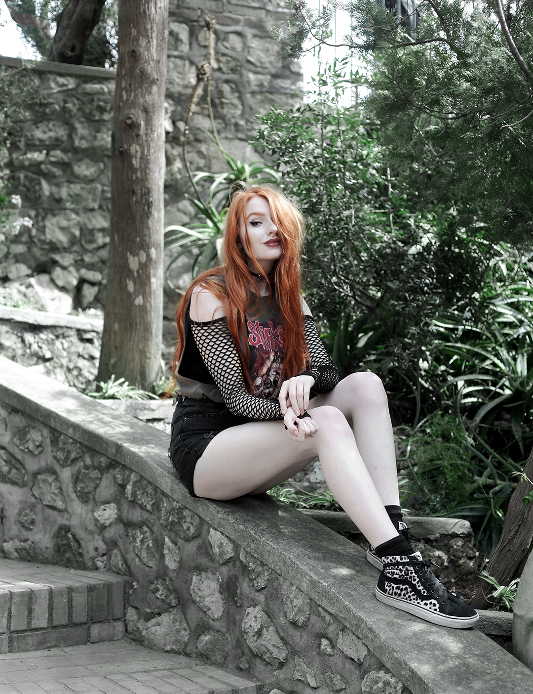 Olivia Emily Wears Slipknot Tank Band Tee, Asos Fishnet Sleeve Bodysuit, Black Denim Shorts, and Vans Snow Leopard Sk8 Hi high tops