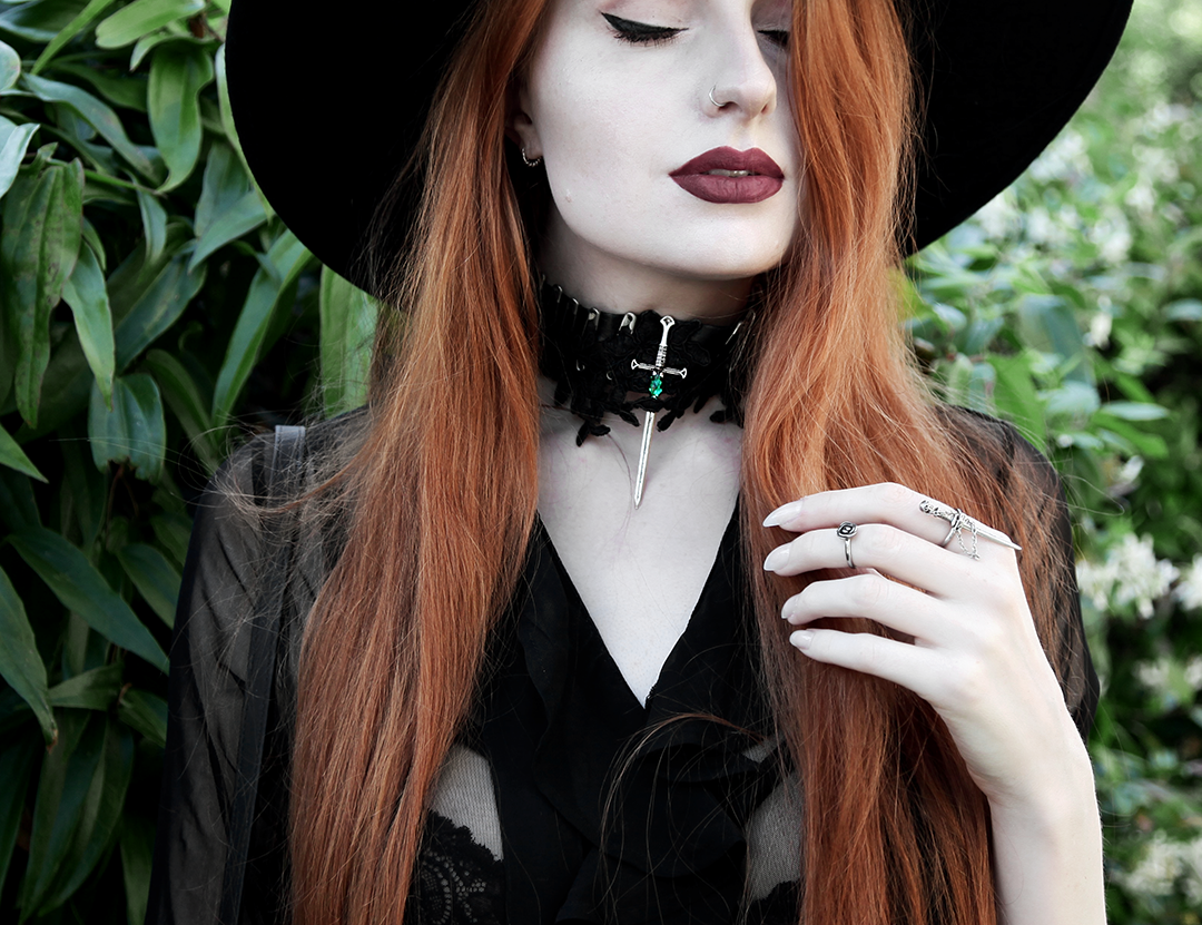 Olivia Emily wears Killstar Witch Brim Hat, Killstar Decay Nu-Mourning dress, House of Need Sword Ring, and Pheren Couture Sword Choker
