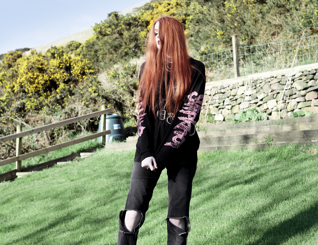 Olivia Emily wears Slipknot Band Tee, Asos ripped straight leg jeans, pothole fishnet socks, and Dr Martens boots