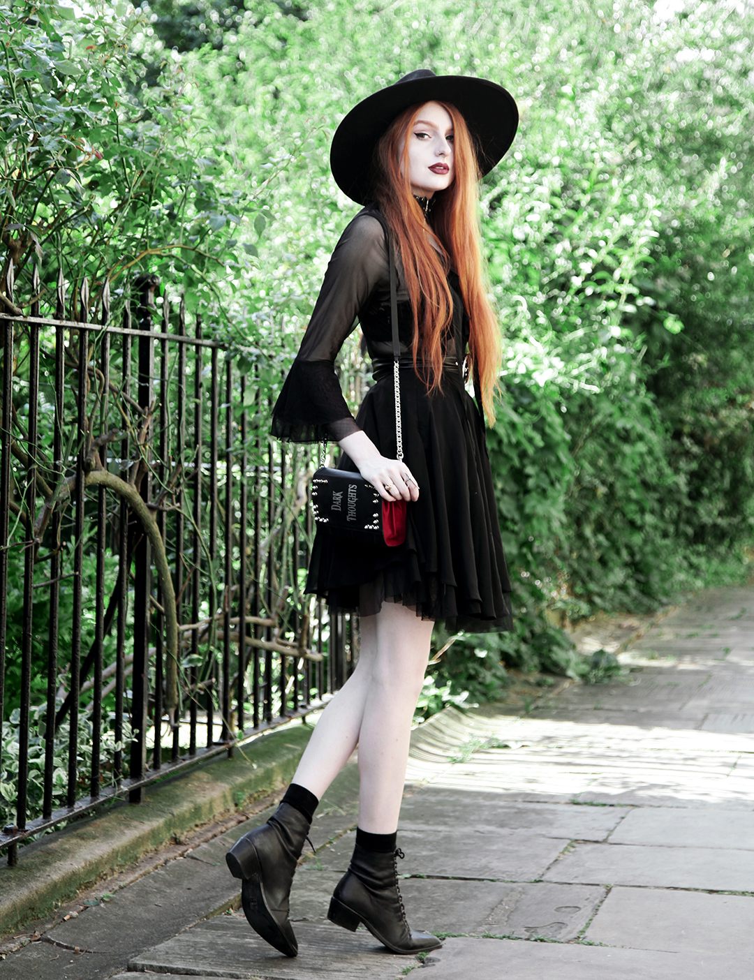 Olivia Emily wears Killstar Witch Brim Hat, Killstar Decay Nu-Mourning dress, Pheren Couture Sword Choker, Skinnybags Dark Thoughts Book Clutch and Asos Pointed Toe Boots