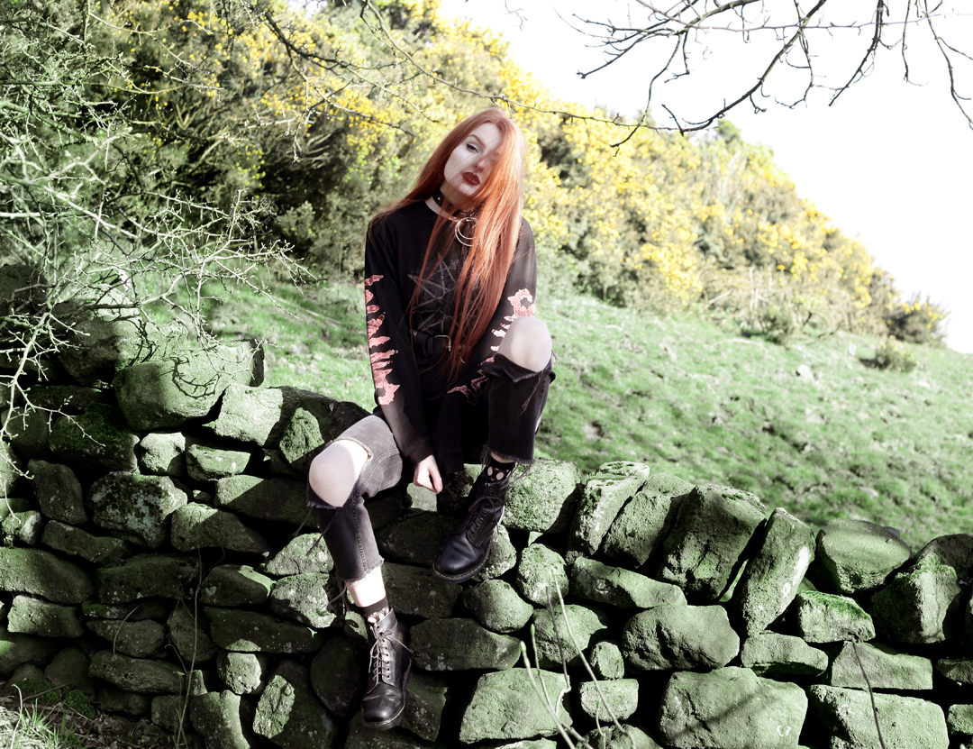 Olivia Emily wears Slipknot Band Tee, Asos ripped straight leg jeans, pothole fishnet socks, and Dr Martens boots