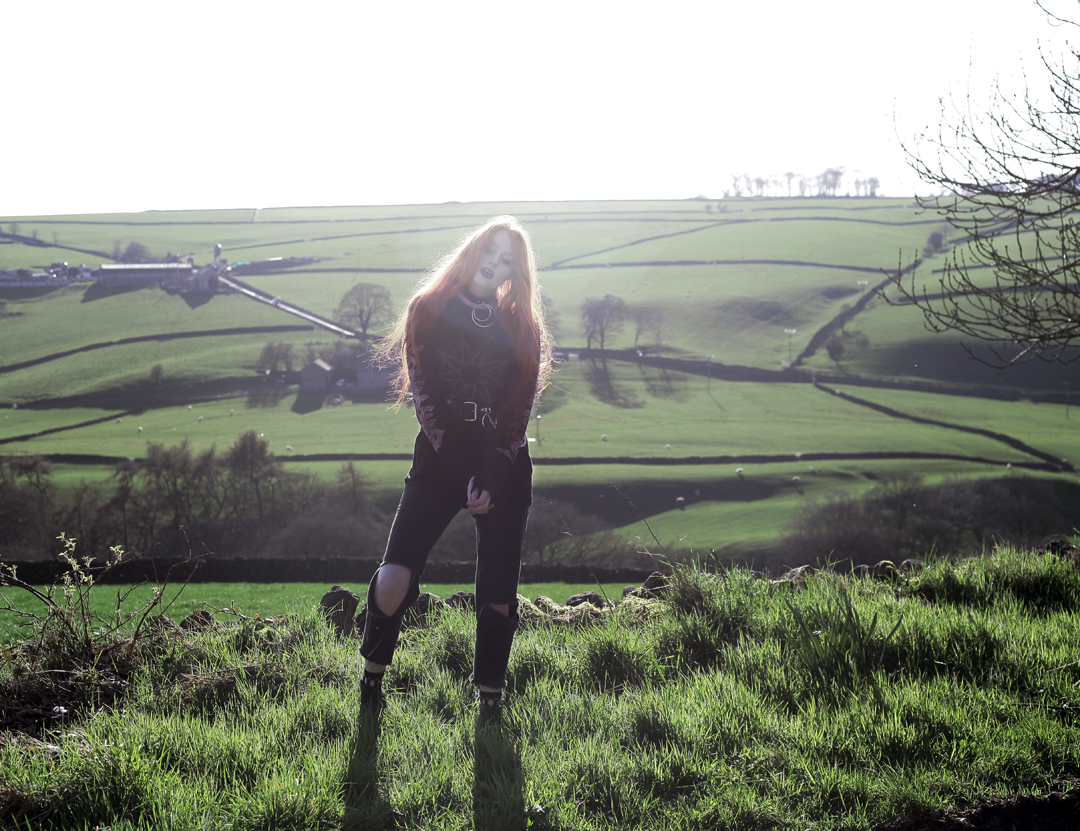 Olivia Emily wears Slipknot Band Tee, Asos ripped straight leg jeans, pothole fishnet socks, and Dr Martens boots